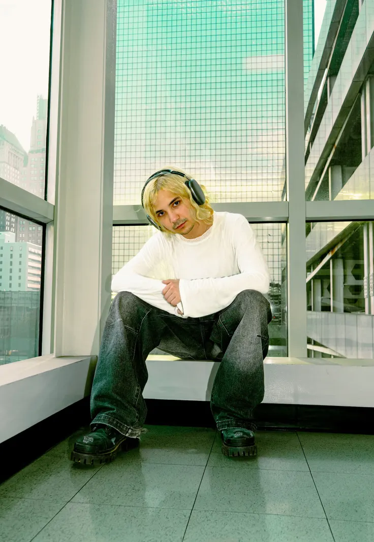 Jordan Andrew sitting by a glass window in headphones