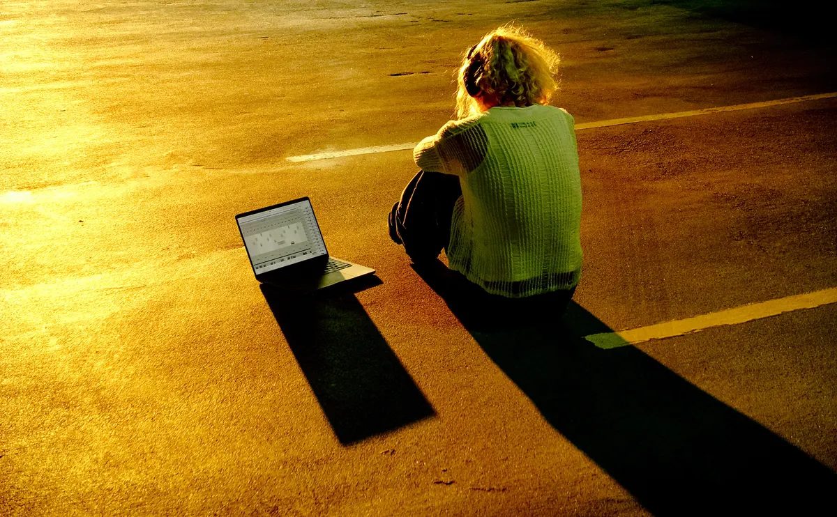 Jordan Andrew on a rooftop parking deck at sunset with a laptop
