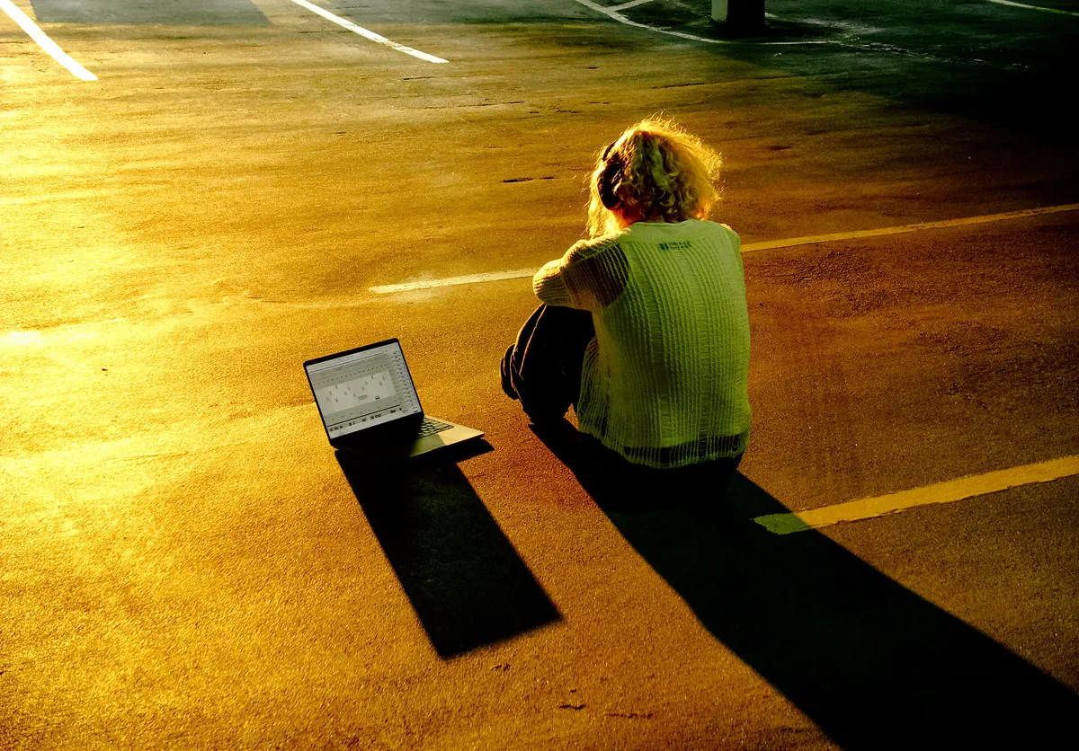 Jordan Andrew sitting on a rooftop at golden hour with a laptop