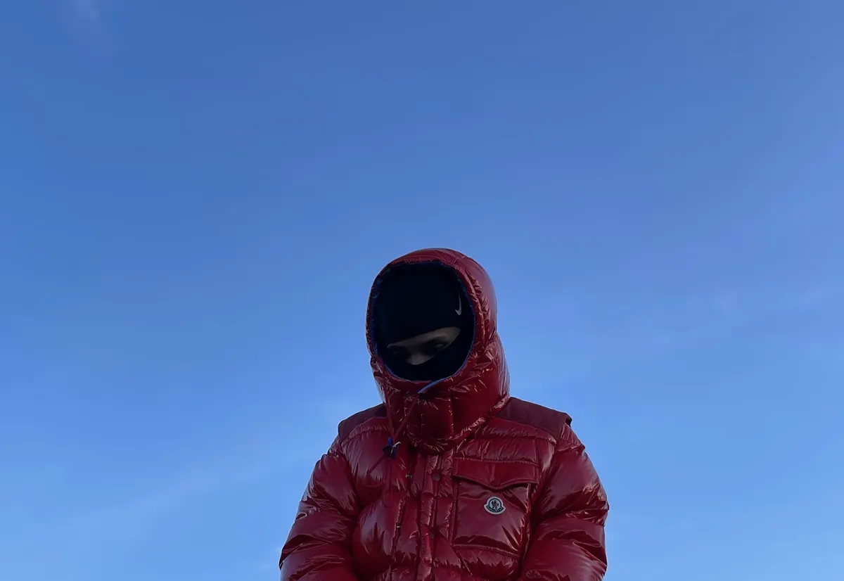 Jordan Andrew in a red puffer jacket under a clear blue sky