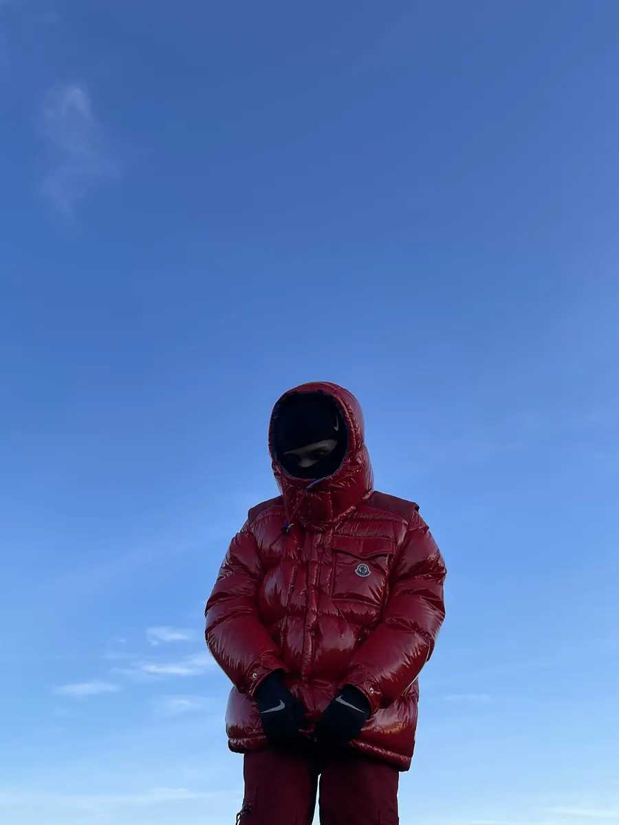 Jordan Andrew in a red puffer jacket against a blue sky