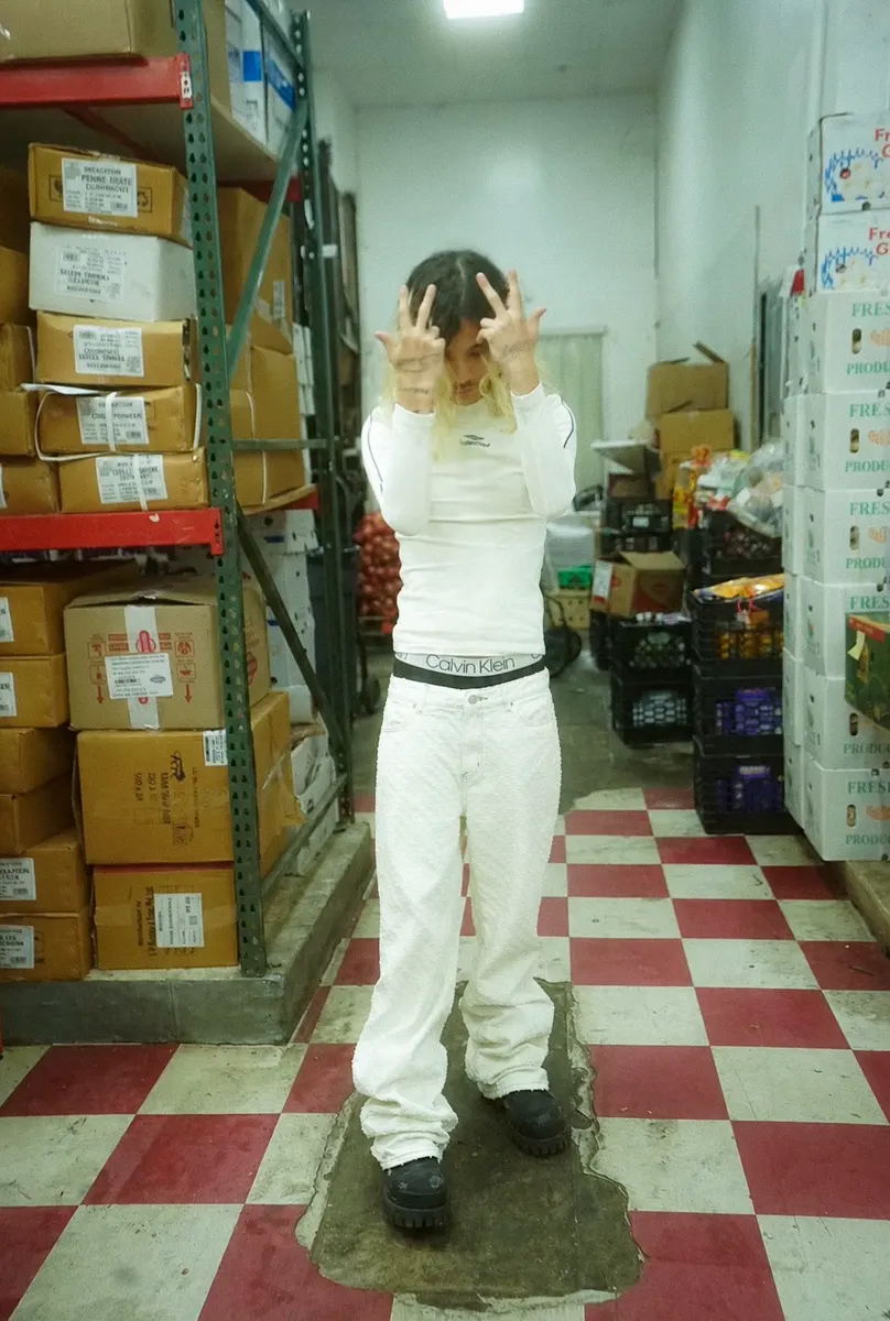 Jordan Andrew in white in a stockroom with a checkered floor